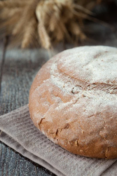 Round loaf of bread and wheat ears — Stock Photo, Image