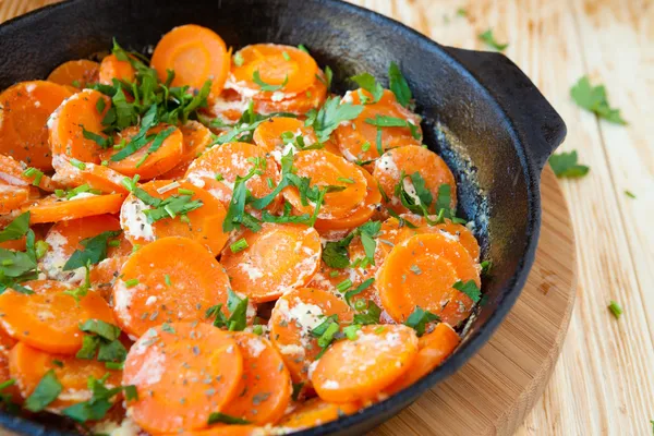 Carrots and sour cream in a frying pan with herbs — Stock Photo, Image