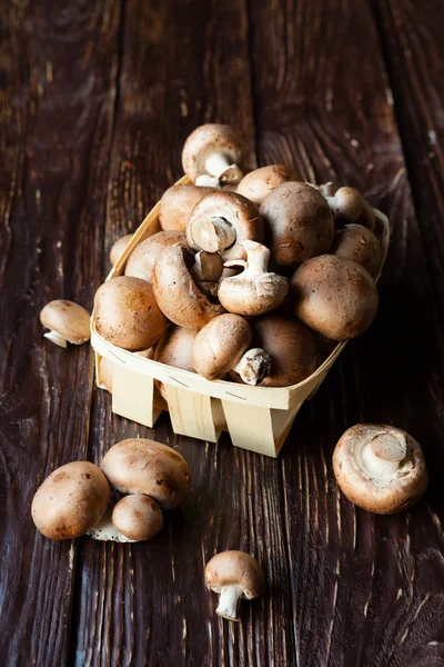 Cogumelos em uma cesta em conselhos escuros — Fotografia de Stock