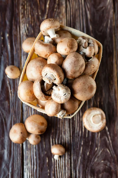 Fresh champignons in a basket on dark boards — Stock Photo, Image