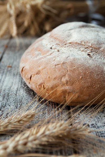 Round loaf grain bread and wheat ears — Stock Photo, Image