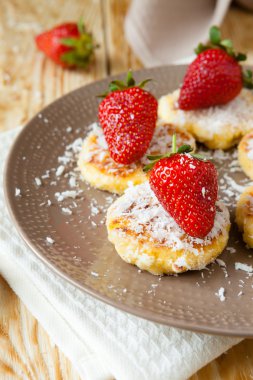 Cheesecakes pudra şekeri ve üst çilek ile