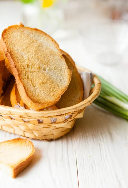 Pan tostado en la cesta de pan sobre tablas blancas —  Fotos de Stock
