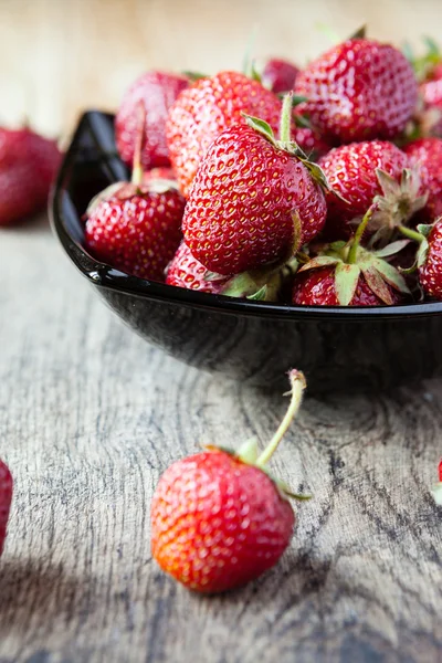 在表上黑碗中的新鲜草莓 — 图库照片