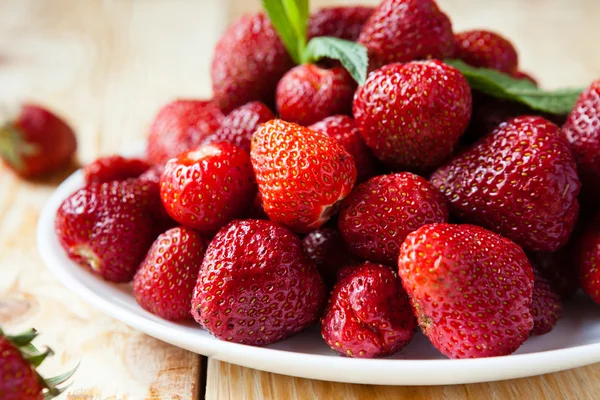 Fresh juicy strawberries on a white plate — Stock Photo, Image