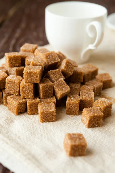 Bunch of raw sugar and white cup — Stock Photo, Image