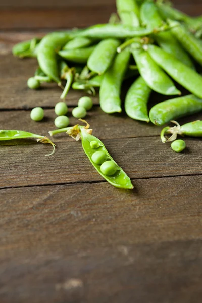 Handful of green peas on wooden boards — Stock Photo, Image