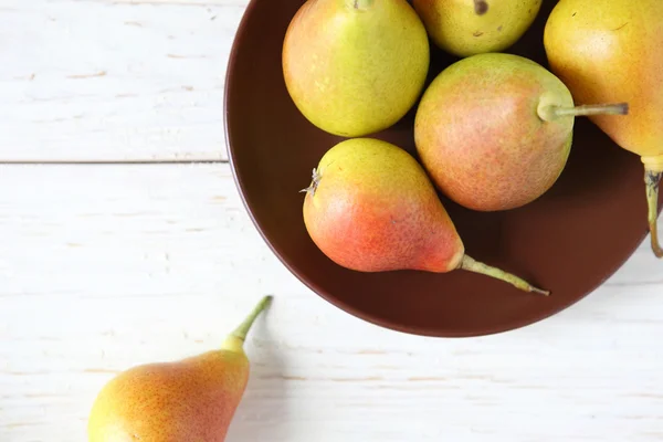 Ripe juicy pear and a clay plate — Stock Photo, Image