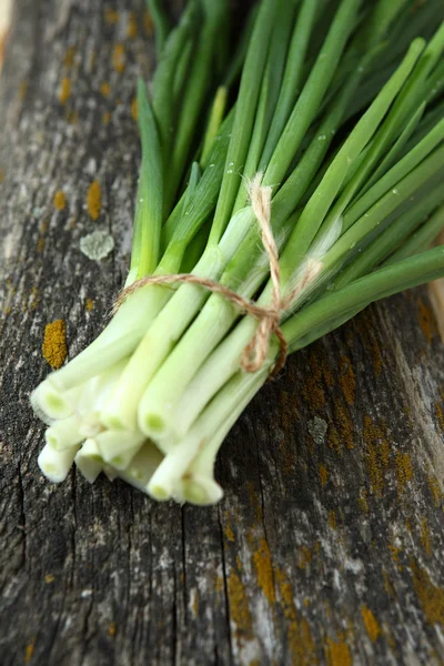 Verse groene uien op het oude bord — Stockfoto