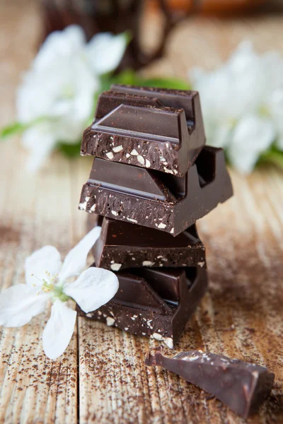 Pedaços de chocolate escuro e flores brancas — Fotografia de Stock
