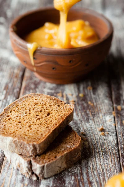 Skivor mörkt bröd och honung i en lera skål — Stockfoto