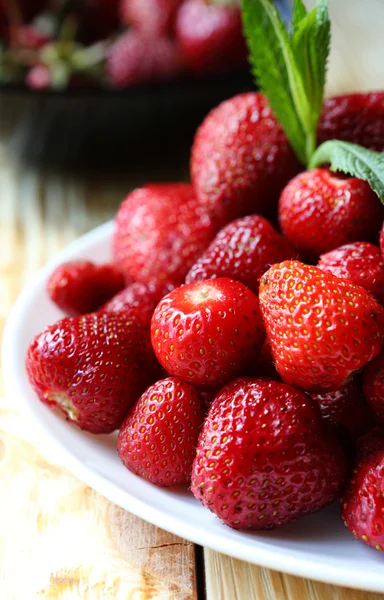 Pile ripe strawberries on a white plate — Stock Photo, Image