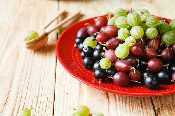 Ripe gooseberries and currants on a plate — Stock Photo, Image