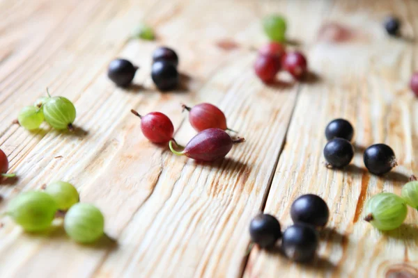 Gooseberries and currants on wooden table — Stock Photo, Image