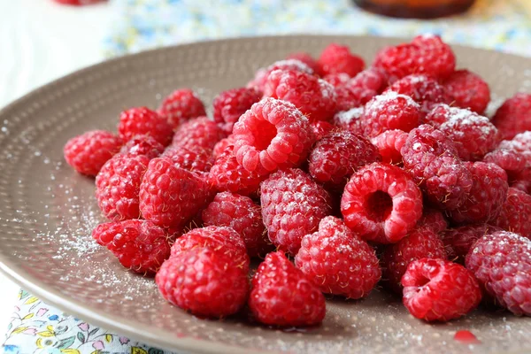 ripe raspberries on a plate with icing sugar