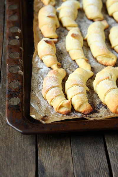 Small freshly baked croissants on a baking sheet — Stock Photo, Image