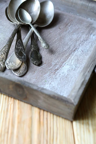 Old spoons in a wooden tray — Stock Photo, Image