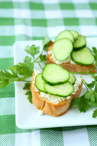 Bruschetta with cheese and fresh cucumber on a plate — Stock Photo, Image