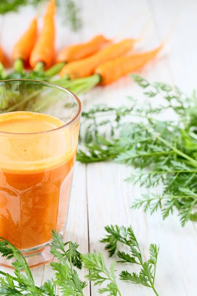 Manojo de zanahorias frescas y un vaso de jugo — Foto de Stock