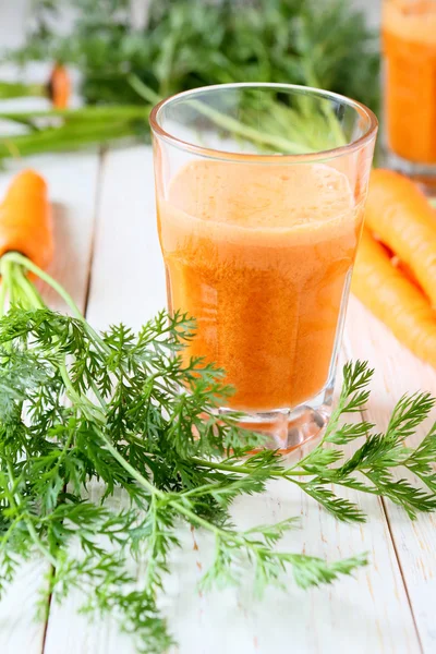 Jugo en un vaso transparente y zanahorias frescas — Foto de Stock