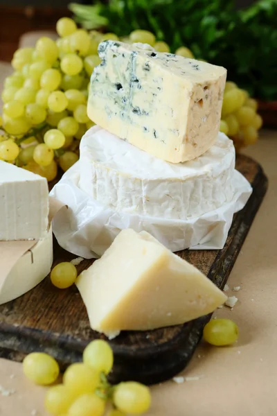 ブドウの背景上にチーズの種類různé druhy sýra, na pozadí hroznů — Stock fotografie