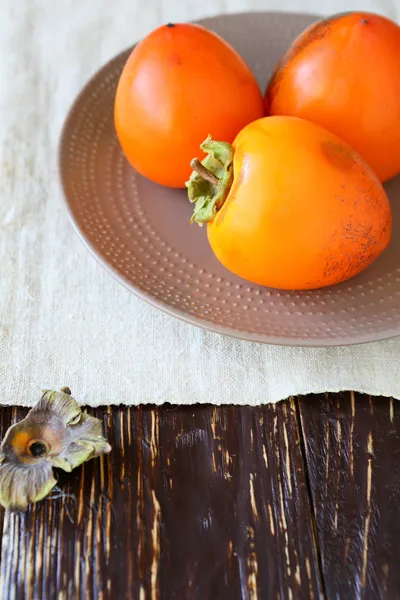 Juicy ripe persimmon on a plate — Stock Photo, Image