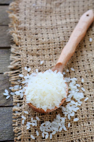 Uncooked rice on wooden spoon — Stock Photo, Image