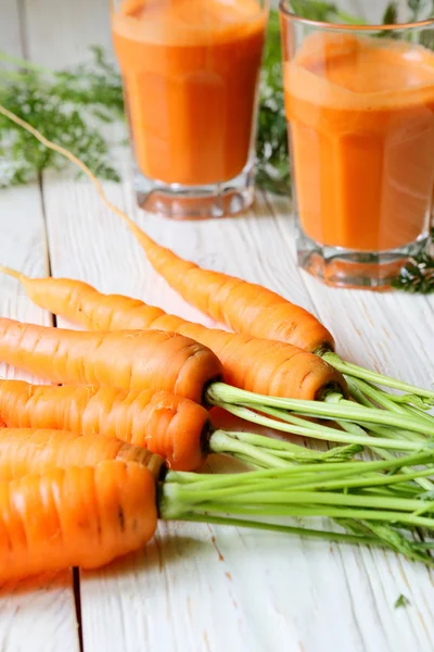 Carrot on the table and two glasses of juice — Stock Photo, Image