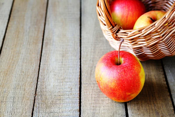 熟透了的苹果和一篮子上木制的背景 — 图库照片