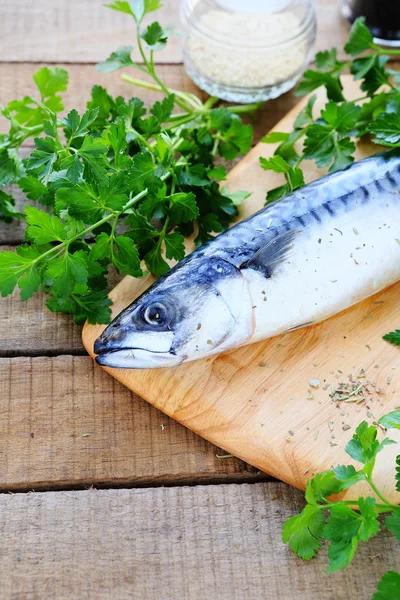 Raw fish, greens on a chopping board — Stock Photo, Image