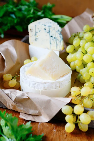 Queijo de cabra, parmesão, brie e camembert com uvas — Fotografia de Stock