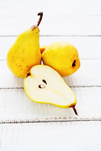 Drei reife Birnen auf einem weißen Tisch — Stockfoto