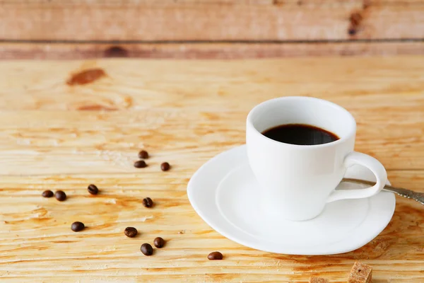 Beker van's ochtends koffie op houten achtergrond — Stockfoto