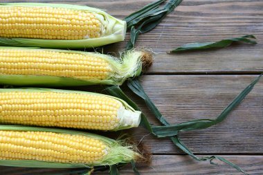 mısır koçanı ve ahşap zemin üzerine yeşil yaprakları