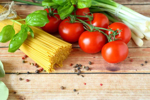 Spaghetti, basilika och tomater på trä bakgrund — Stockfoto