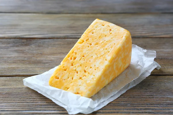 Chunk of yellow cheese on a wooden background — Stock Photo, Image