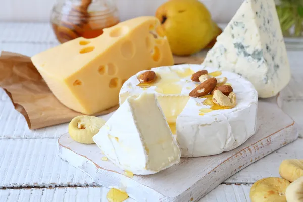 Três tipos de queijo e mel sobre um fundo branco — Fotografia de Stock