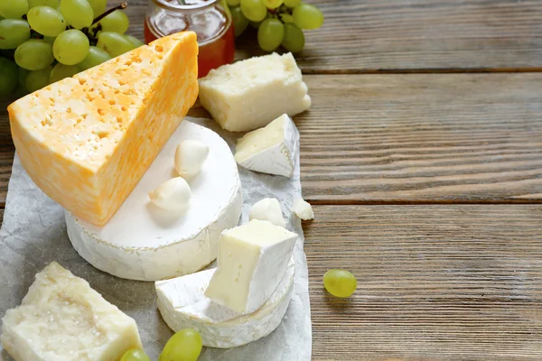 Käse mit Trauben auf Holzgrund — Stockfoto