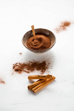 Tarçın çubukları ve toz kasenin beyaz yüzeyinde