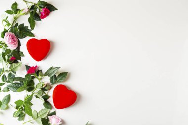 Küçük bahçe gülleri ve ışık yüzeyindeki kırmızı kalplerin yukarıdan görünüşü kopyalama alanı