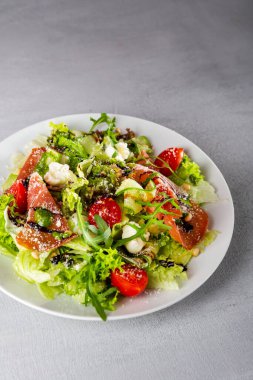 Close up of fresh salad with ham and cheese on white plate