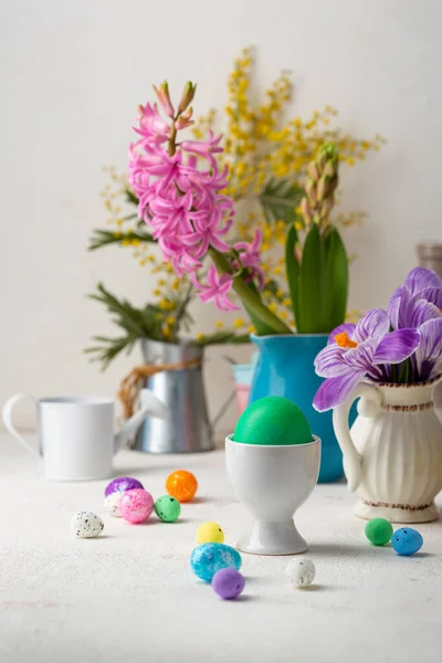 一个绿色的复活节彩蛋和鲜花放在小桌子上的花瓶里 — 图库照片