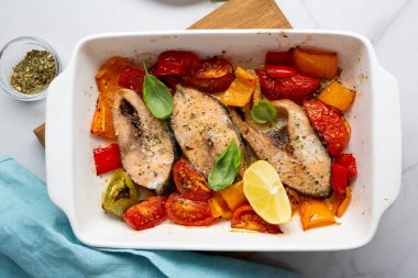 Kızarmış balık bifteği ve sebzeler beyaz tabakta sağlıklı yiyecekler.