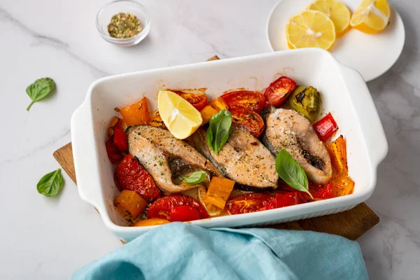 Roasted salmon steak with vegetables in baking dish food on marble table
