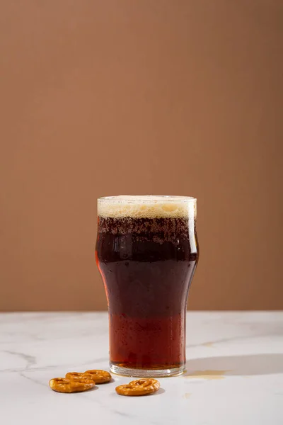 One glass of brown beer with foam on top  food and drink