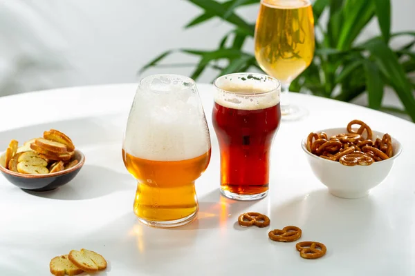 Three glasses with beer light craft dark and snacks