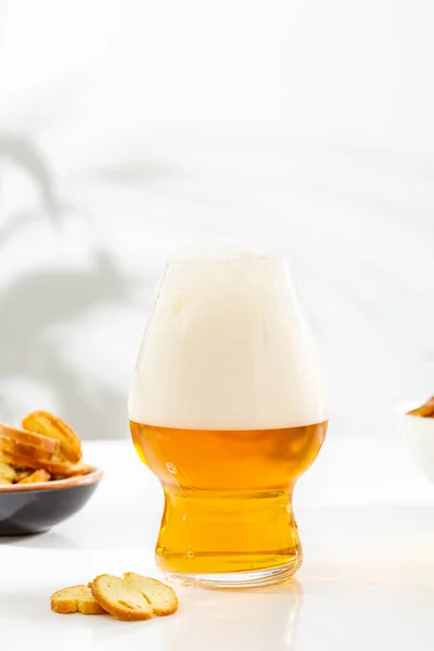 One glass of light beer with foam white surface food and drink