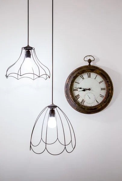 Reloj vintage en una pared blanca con lámparas elegantes —  Fotos de Stock