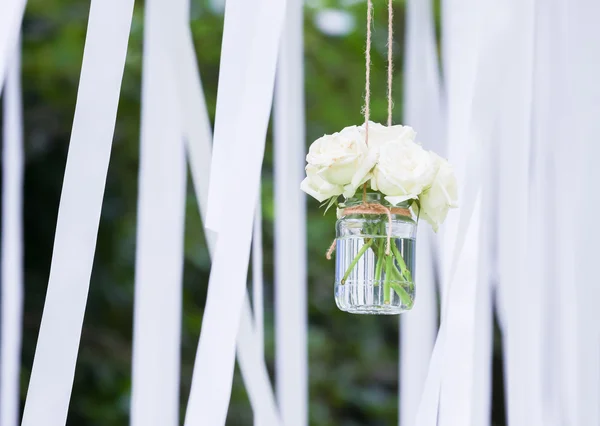 Rosas blancas en un jarrón de vidrio con cintas blancas —  Fotos de Stock