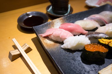 yemek çubukları ile siyah bir tabak taze sushi